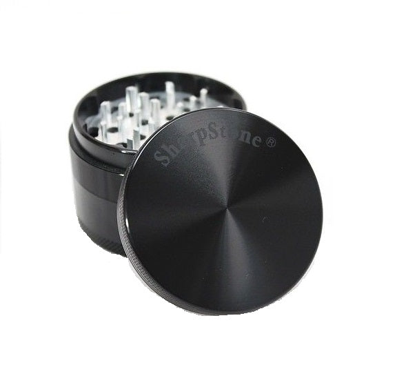 A black, four-part herb grinder with its lid slightly ajar, revealing silver grinding teeth inside. The brand 'Sharpstone' is visible on the lid.