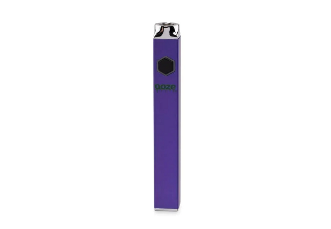 A sleek, rectangular purple vaporizer battery stands upright, featuring a black hexagonal button and a green 'Ooze' logo on its front. The top and bottom are silver.