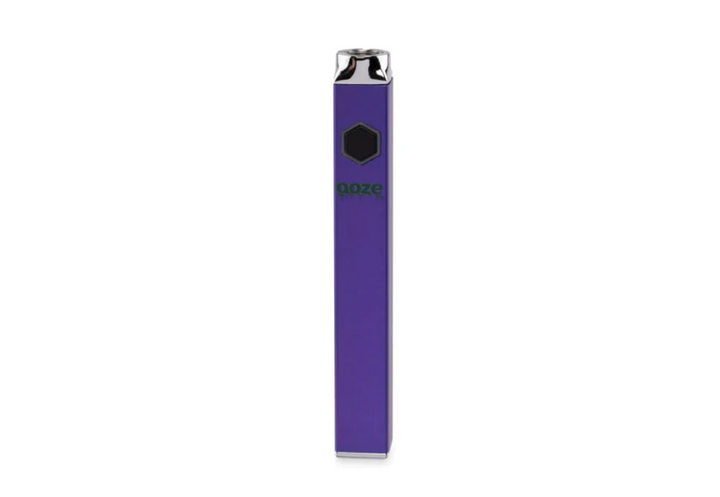 A sleek, rectangular purple vaporizer battery stands upright, featuring a black hexagonal button and a green 'Ooze' logo on its front. The top and bottom are silver.