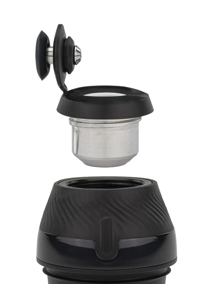 Detail shot of a portable vaporizer's disassembled components, showing the black silicone cap with a metal insert and the textured black base.