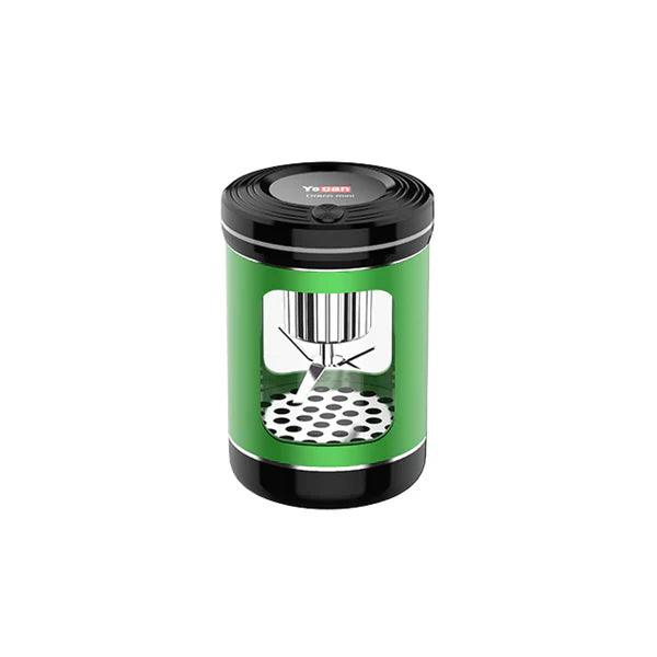 A green and black cylindrical electric dry herb grinder with a clear window showing internal blades and a perforated base, set against a white background.