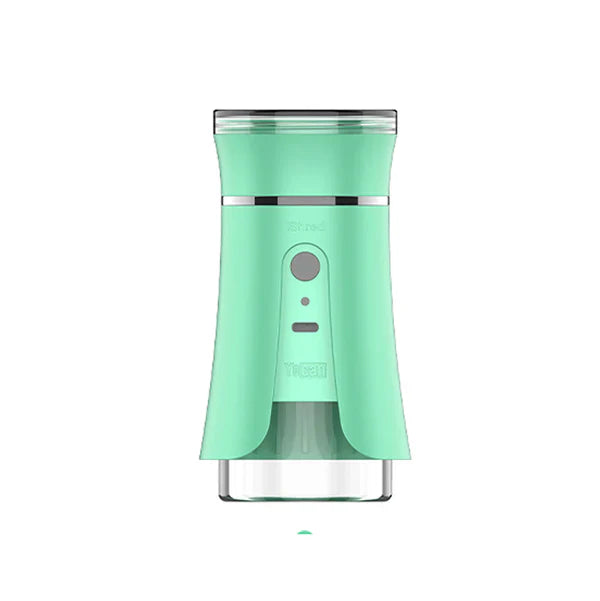 Front view of a mint green electric dry herb grinder with a clear bottom chamber and silver accents, featuring a power button and 'Shred' text.