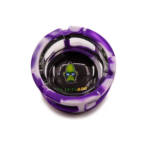 Top-down view of a round ashtray featuring a purple and white marbled silicone sleeve around a clear glass interior, with a green alien ape logo at the bottom.