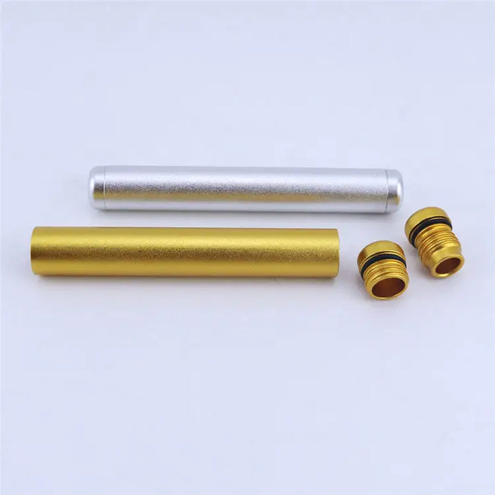 Two cylindrical aluminum tubes, one gold and one silver, are displayed horizontally on a white surface. Two small gold threaded caps with black O-rings are placed next to the gold tube, suggesting they are detachable parts.