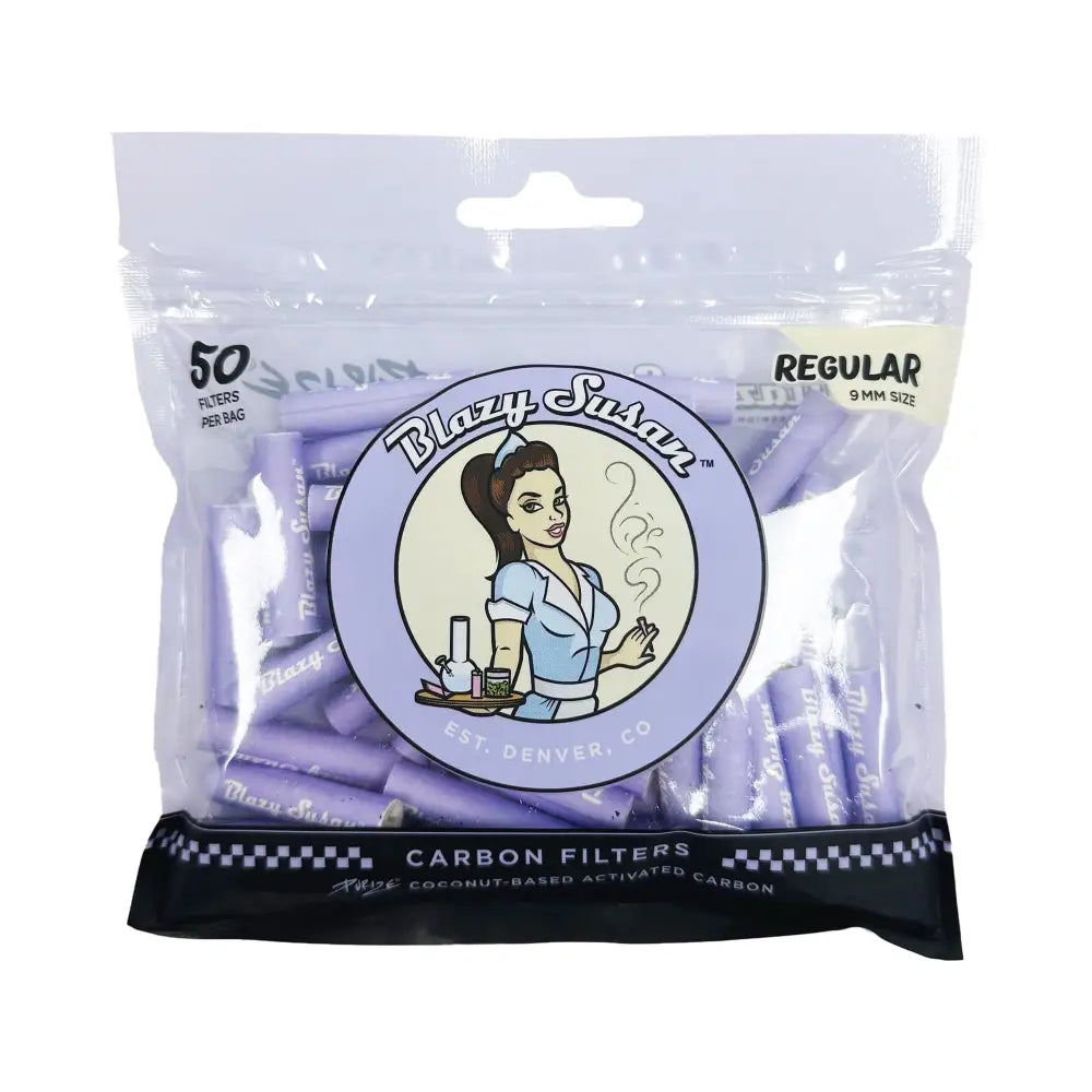 A clear plastic bag filled with numerous small, cylindrical purple filter tips. The bag features a circular logo with a cartoon woman in a diner uniform, holding a cigarette, with the brand name 'Blazy Susan' and 'EST. DENVER, CO'. Text on the bag indicates '50 FILTERS PER BAG' and 'REGULAR 9MM SIZE'. The bottom of the bag is black with a checkered pattern and text 'CARBON FILTERS'.