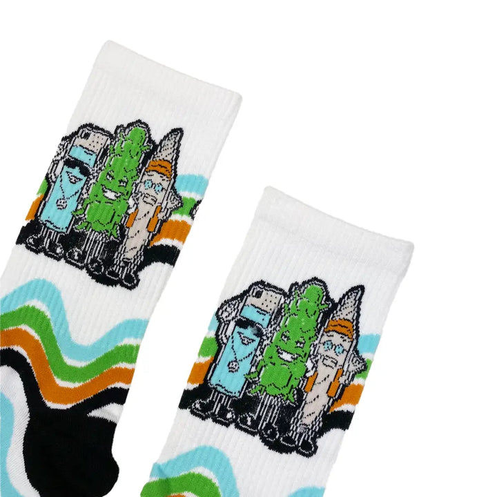 Close-up detail shot of two white crew socks featuring cartoon characters of a blue lighter, a green cannabis bud, and a brown pre-roll, with wavy stripes in blue, green, orange, and black.