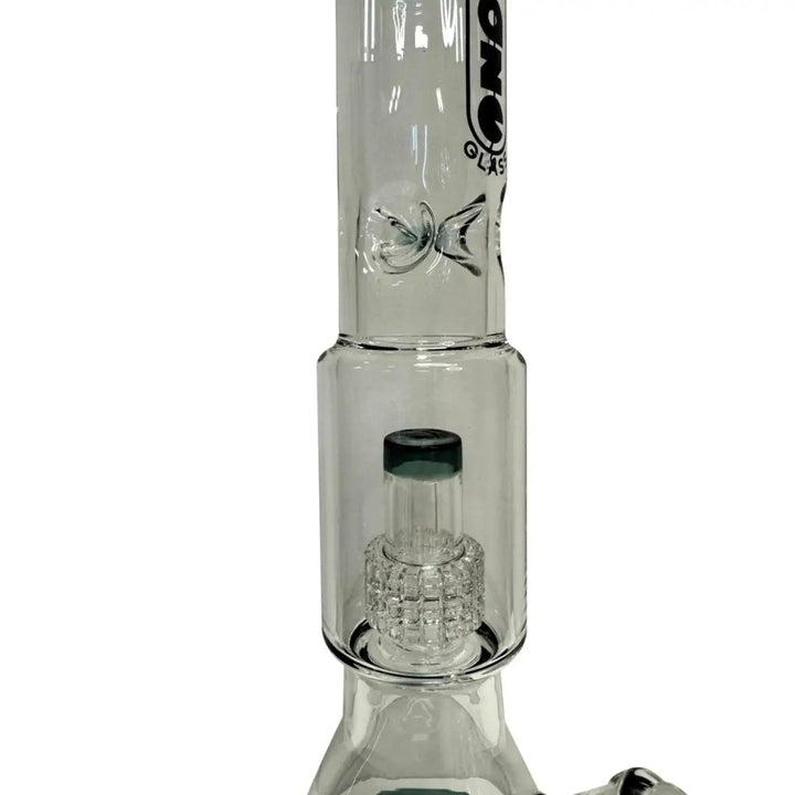 Close-up detail shot of the middle section of a clear glass water pipe, showcasing the disc percolator with a dark green accent and the ice pinch above it.