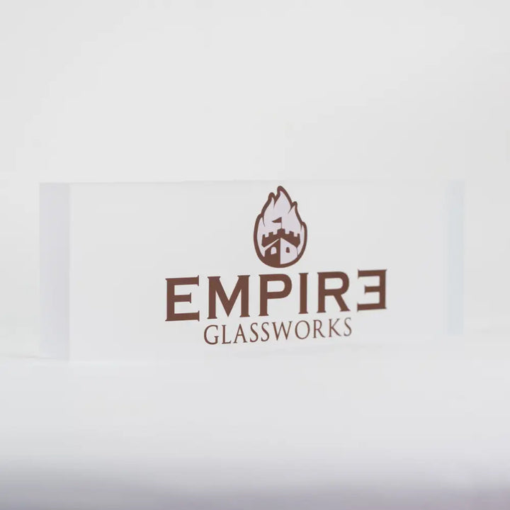 A clear rectangular acrylic plaque with the brown 'Empire Glassworks' logo, featuring a castle with flames, centered on a white background.