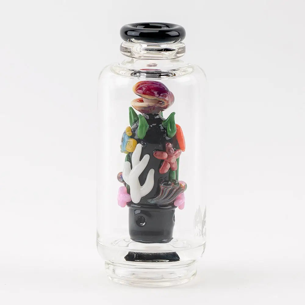 A clear glass vaporizer attachment featuring an intricate, colorful underwater reef scene with coral, a clamshell, and seaweed, all encased within the cylindrical glass.