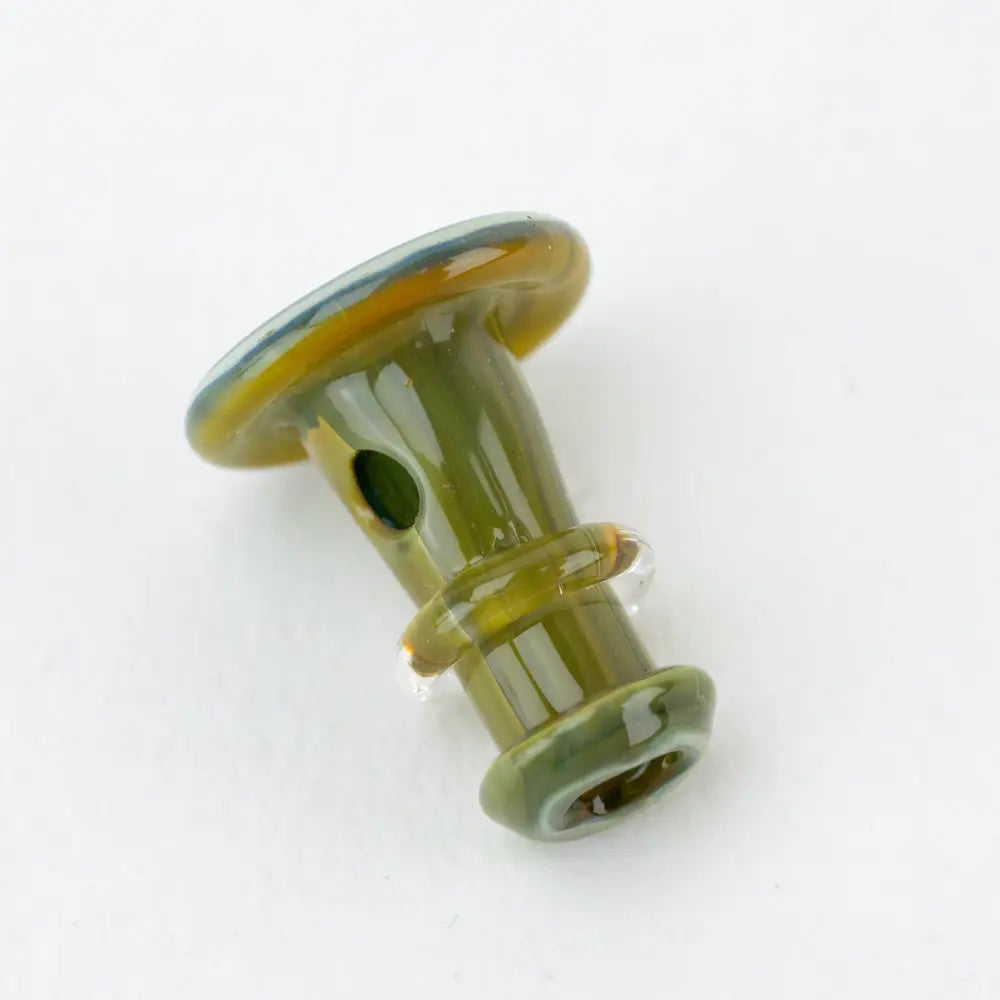 Small, glossy glass accessory with a flared top and bottom, primarily green with amber and blue accents, featuring a small circular opening on its side.