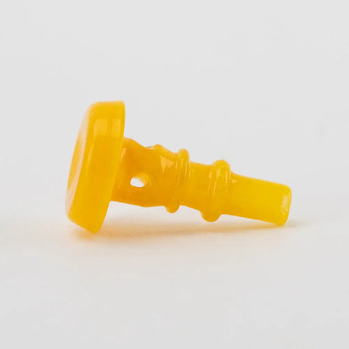Close-up side view of a bright yellow glass accessory, featuring a flat circular end and a tapered body with small holes and ridges, against a white background.
