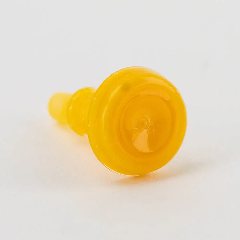 Close-up view of a small, bright yellow glass accessory, cylindrical in shape with a wider, flat top and a tapered base, against a white background.