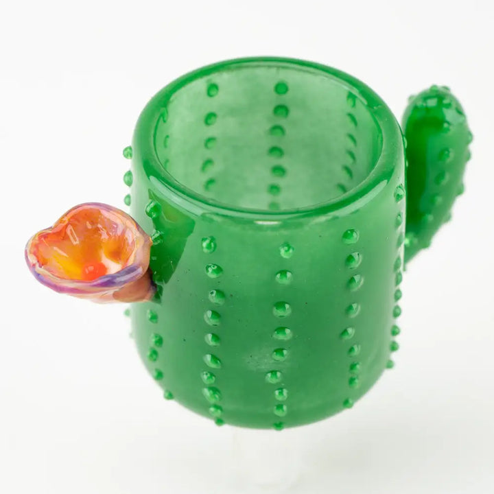 Close-up detail shot of a green glass cactus-shaped attachment, featuring small raised bumps and a colorful orange and purple flower on the side, against a white background.