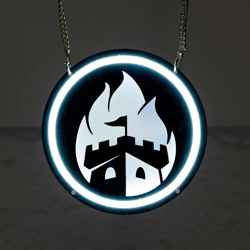 A circular neon sign featuring a white glowing castle and flame logo, surrounded by a bright white neon ring, hanging by two metal chains against a dark background.