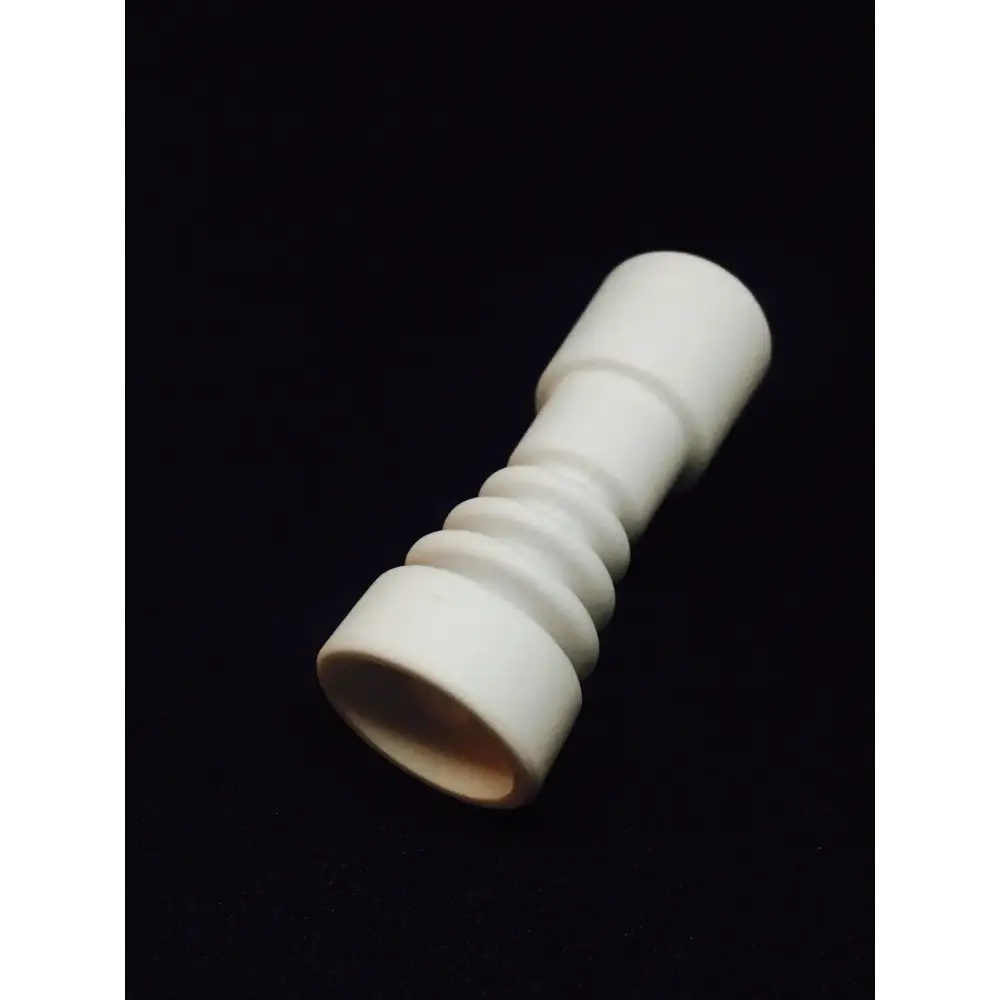 Close-up of a white ceramic dabbing nail, featuring a cylindrical body with ribbed sections and a wider, open base, set against a dark background.