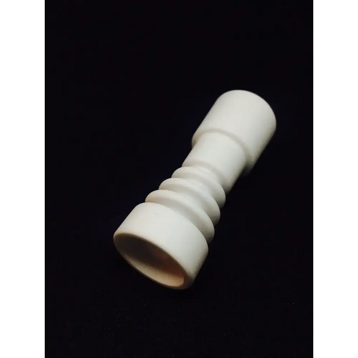 Close-up of a white ceramic dabbing nail, featuring a cylindrical body with ribbed sections and a wider, open base, set against a dark background.