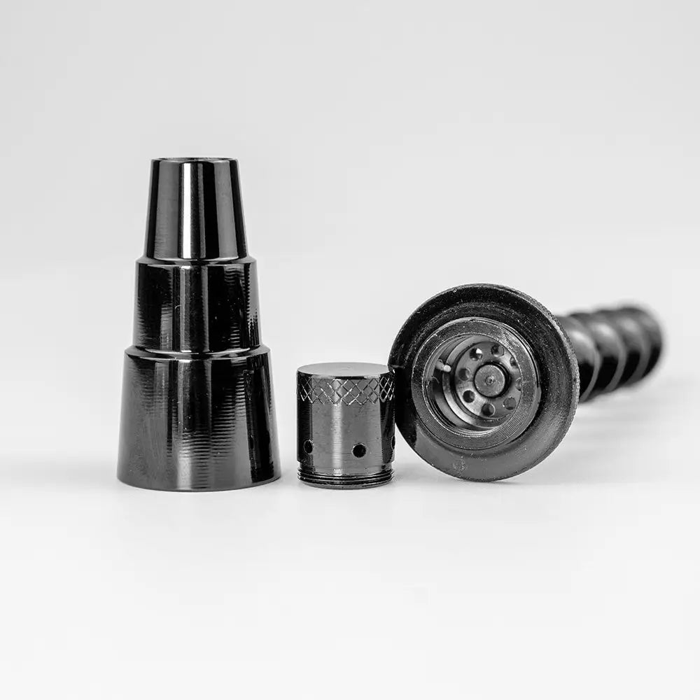 Close-up of three disassembled dark metal components, including a conical piece, a small cylindrical piece with knurling, and a larger piece with an internal mechanism, all laid out on a white surface.