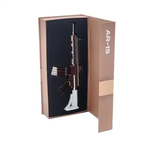 A rifle-shaped electric nectar collector kit displayed in an open, reddish-brown box with 'AR-15' printed on the lid. The item is dark brown and black, resting on a white stand.