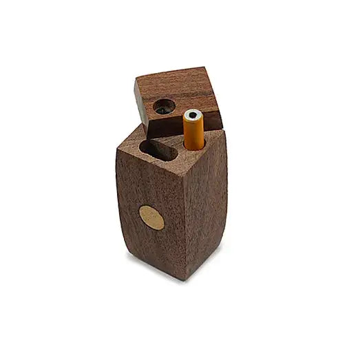 Close-up of a dark brown wooden dugout, partially open, revealing an orange-tipped one-hitter inside. A small brass-colored circular inlay is visible on the side.