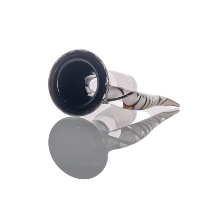 Close-up, top-down view of a glass bowl with a black, textured rim and a clear stem featuring white and brown swirling patterns, reflecting on a white surface.