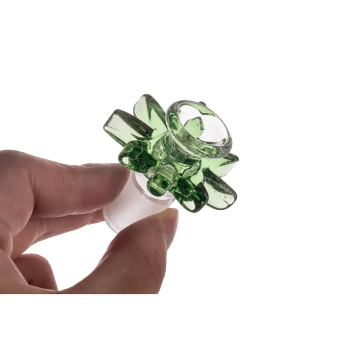 A hand holds a green glass bowl with a flower-like design and a frosted male joint, shown against a white background.