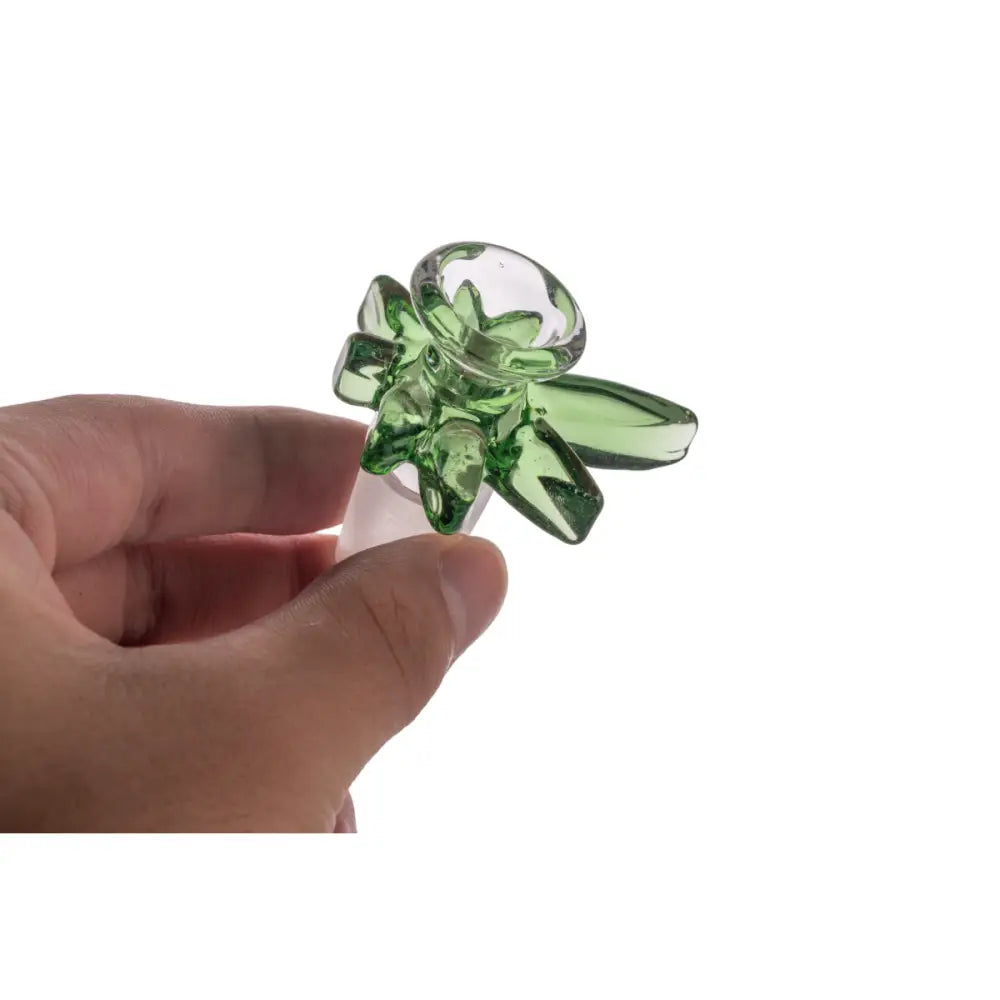 A hand holds a green glass bowl with a flower-like design and an 18mm male joint, shown against a white background.