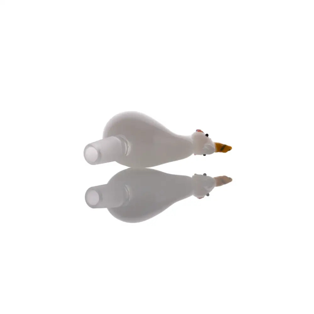 A white glass bowl shaped like a duck with a yellow beak and small red eyes, lying on its side with a clear reflection below it on a white surface.