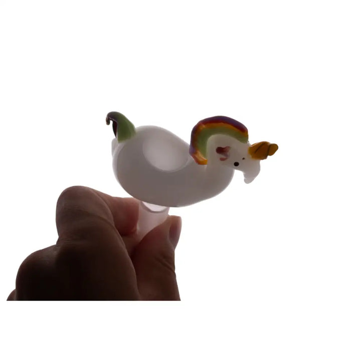 Close-up detail shot of a hand holding a white glass bowl shaped like a whimsical unicorn with a rainbow-colored mane, against a bright white background.