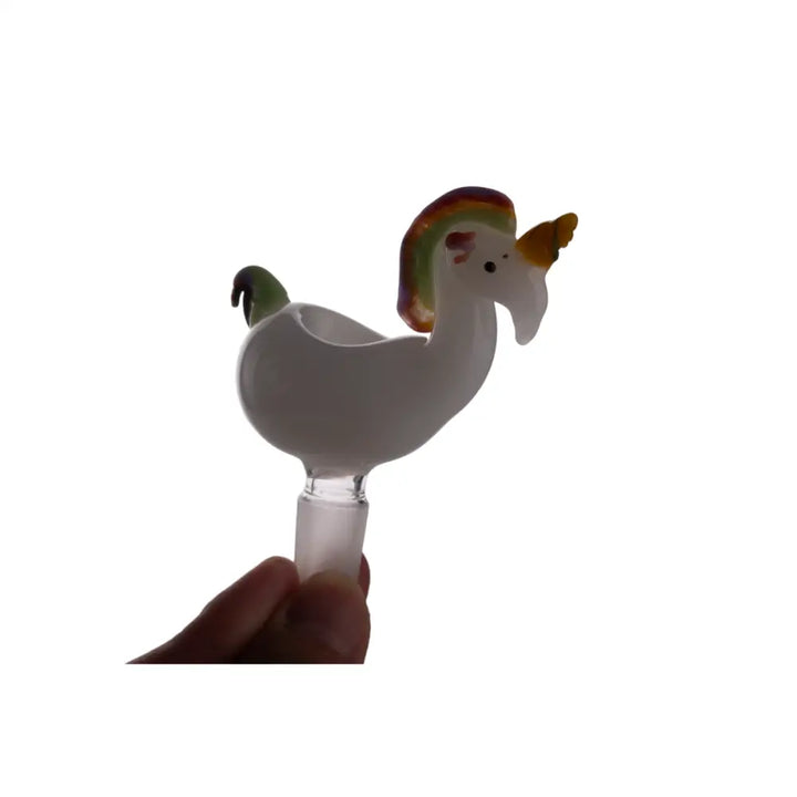 Close-up of a white glass unicorn-shaped bowl with a rainbow mane and yellow horn, held by a hand at its clear male joint.
