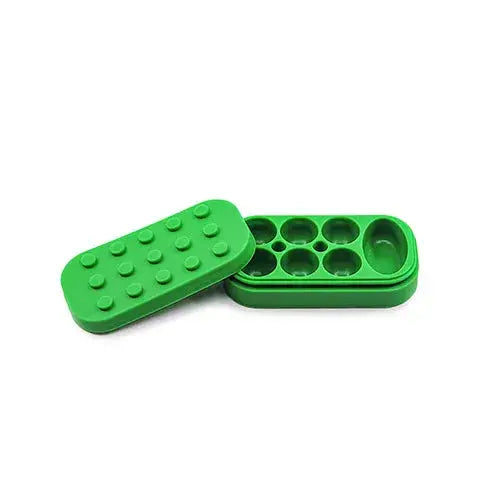 Bright green silicone container with a Lego-style studded lid resting beside its base, which features multiple circular compartments and one larger oval compartment, all against a white background.