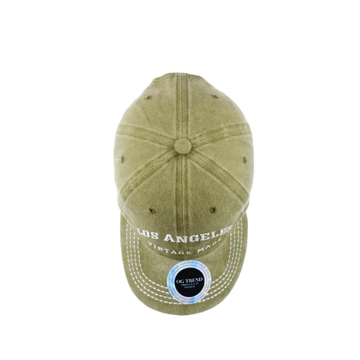 Top-down view of a distressed olive green baseball cap with 'LOS ANGELES' and 'VINTAGE MADE' embroidered in white on the brim, featuring white stitching and a circular sticker on the brim.
