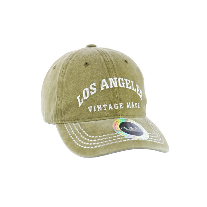 Close-up of a faded olive green baseball cap with 'Los Angeles Vintage Made' embroidered in white on the front, angled slightly.