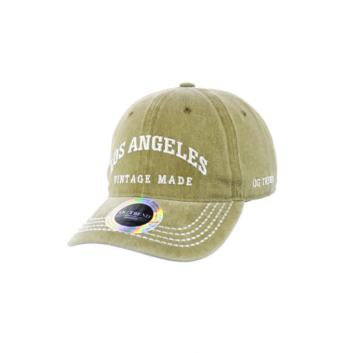 Front view of a faded olive green baseball cap with 'LOS ANGELES' and 'VINTAGE MADE' embroidered in white on the front, and a holographic sticker on the brim.