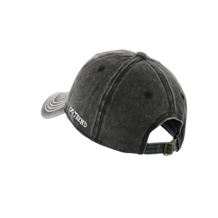 Back-side view of a dark grey distressed baseball cap with white embroidered text 'OG TREND' on the left side and a metal buckle adjustment strap visible at the back.