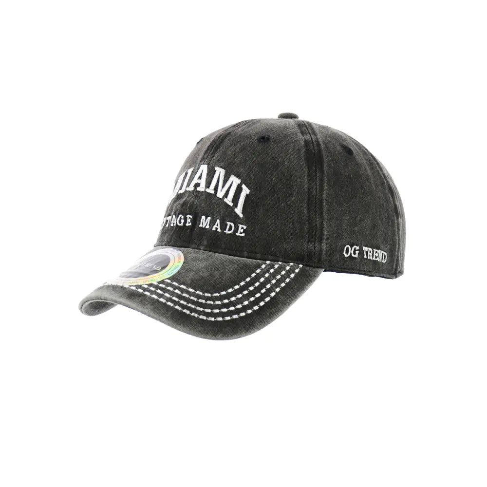A dark grey, distressed baseball cap with white embroidered text 'MIAMI' and 'VINTAGE MADE' on the front, and 'OG TREND' on the side. The brim has white stitching.