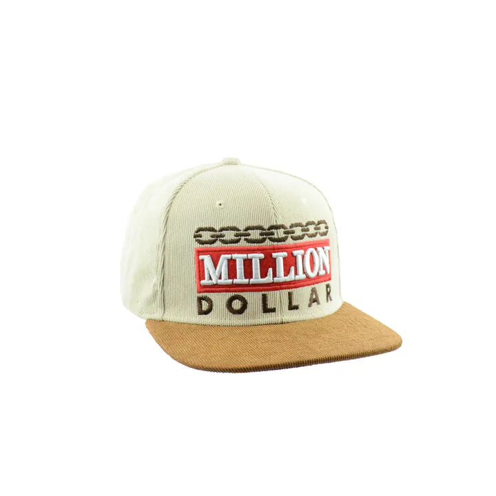 Close-up, angled view of a beige corduroy snapback hat with a brown brim, featuring 'MILLION DOLLAR' text in red and white, and a chain design above it.