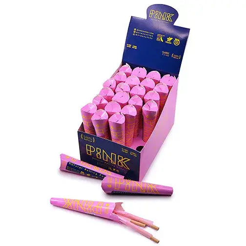 A display box filled with numerous pink pre-rolled cones, with several individual pink cones lying outside the box on a white surface. The cones have gold lettering and patterns.