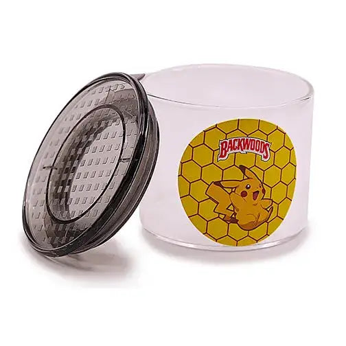 Clear cylindrical glass jar with a dark, textured lid resting open on its side, featuring a yellow circular sticker with a honeycomb pattern, a 'Backwoods' logo, and a Pikachu character.