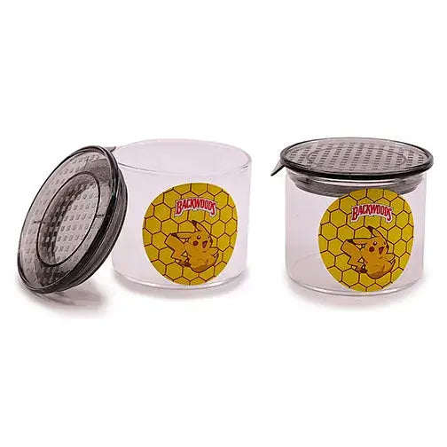 Two clear glass jars with dark gray lids, one open and one closed. Each jar features a yellow circular label with a honeycomb pattern, 'Backwoods' text, and a cartoon Pikachu character.