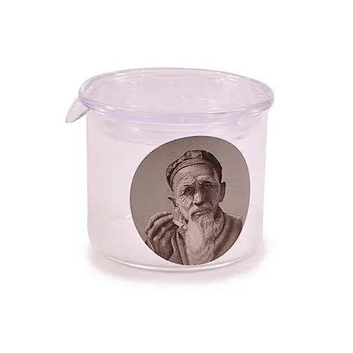 Close-up detail of a clear glass jar featuring a circular grayscale print of an old man with a long white beard and a cap.