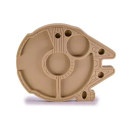 A light brown silicone tray molded into the shape of the Millennium Falcon, featuring multiple compartments and textured details.