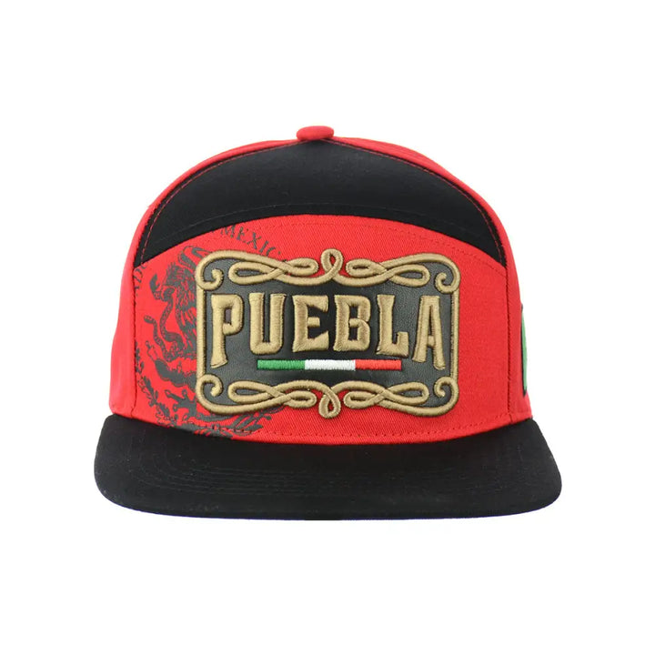 Front view of a red and black snapback hat featuring a prominent 'PUEBLA' embroidery in gold with Mexican flag colors, surrounded by ornate scrollwork, and a subtle eagle design on the left side.