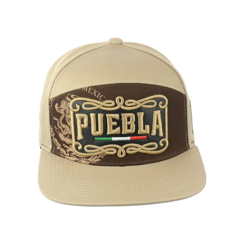 Close-up front view of a beige snapback hat with a brown embroidered patch featuring 'PUEBLA' text, a Mexican flag, and ornate scrollwork.
