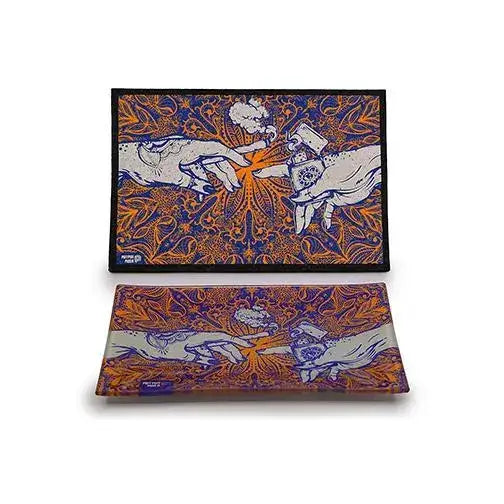 Two rectangular items, a flat mat and a glass tray, are stacked on a white background. Both feature a vibrant blue and orange psychedelic pattern with a central design of two hands, inspired by 'The Creation of Adam', passing a lit joint and a lighter.
