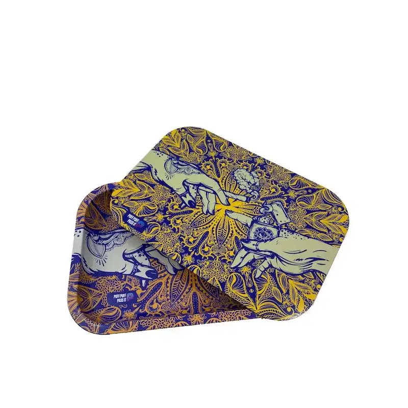 Two rectangular metal rolling trays, one slightly overlapping the other, displaying an intricate blue and yellow pattern of hands reaching towards each other amidst floral and mandala-like designs, set against a white background.