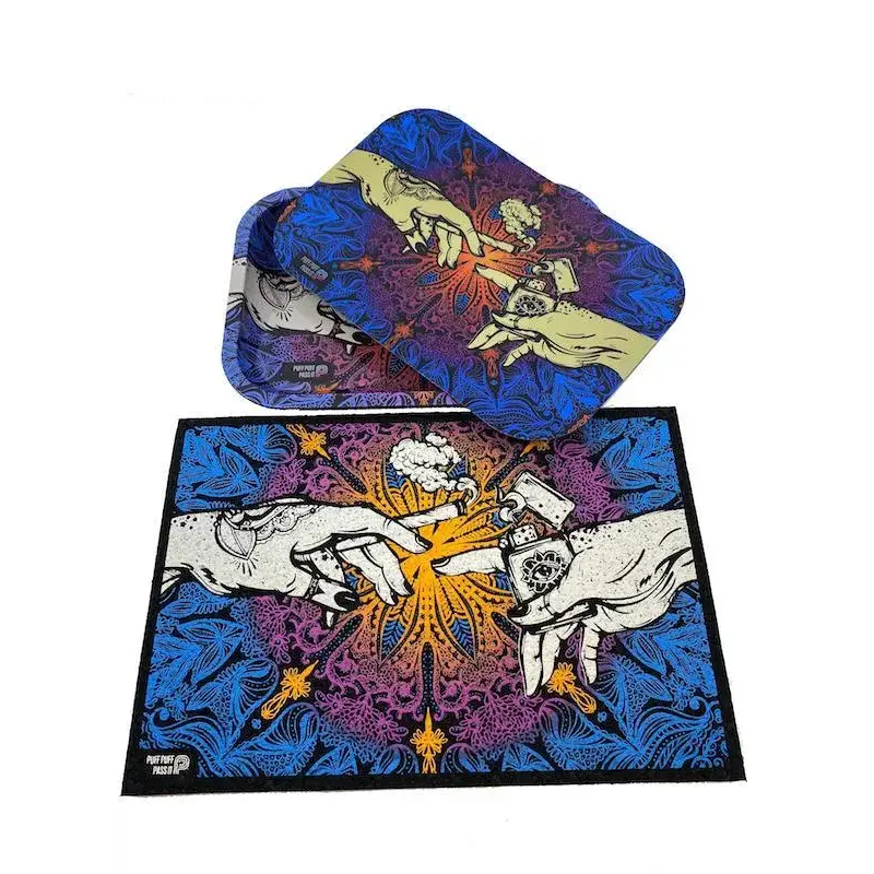 A matching set of a rectangular rolling tray with a lid and a mat, both featuring a psychedelic 'Creation of Adam' parody design with cannabis elements, set against a white background.