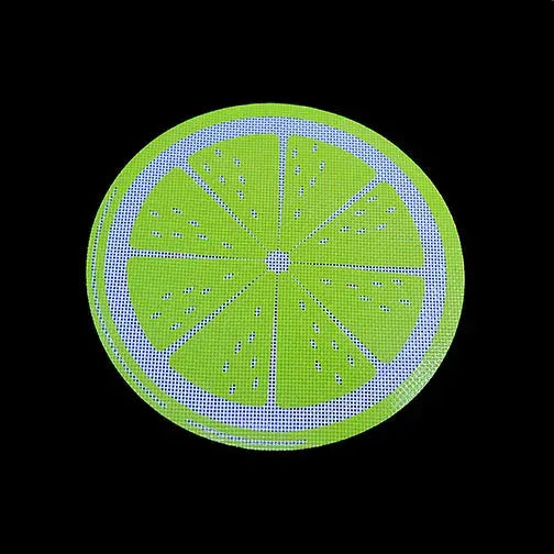 Close-up detail of a round, lime-green silicone dab mat featuring a citrus slice design with blue-white outlines and a dotted texture, set against a solid black background.