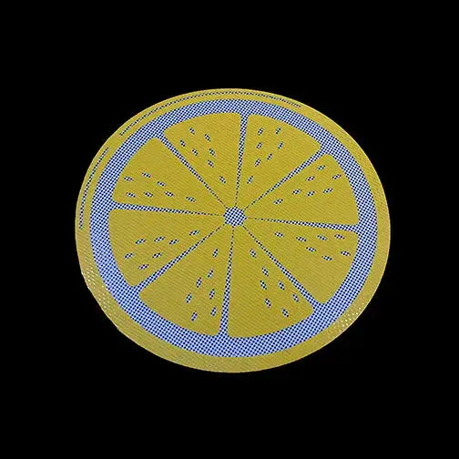 Round yellow silicone mat designed to look like a sliced lemon or citrus fruit, with blue and white polka dot patterns on the rind and segment lines, against a black background.