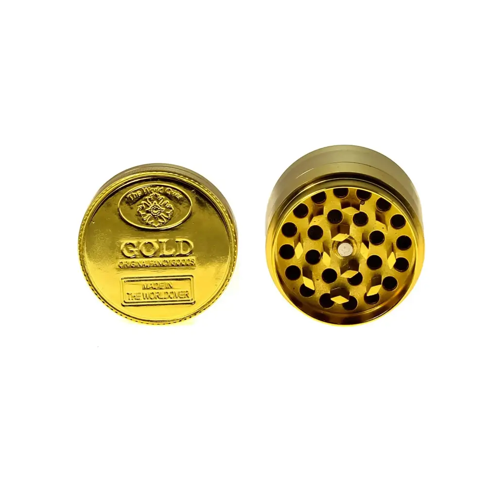 Two views of a shiny gold herb grinder. One view shows the top, designed like a gold coin with embossed text. The other view shows the internal grinding teeth and holes.