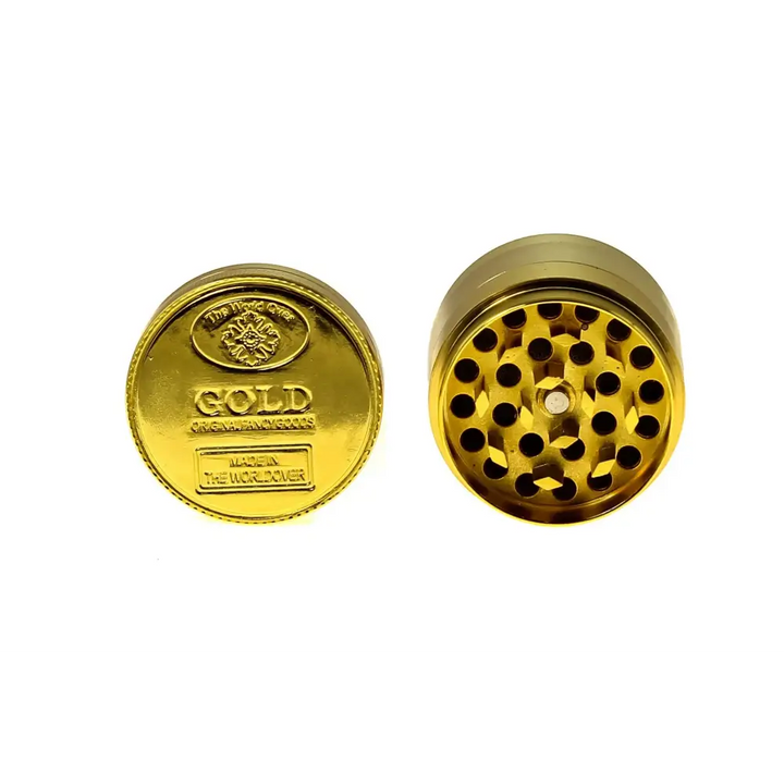 Two views of a shiny gold herb grinder. One view shows the top, designed like a gold coin with embossed text. The other view shows the internal grinding teeth and holes.